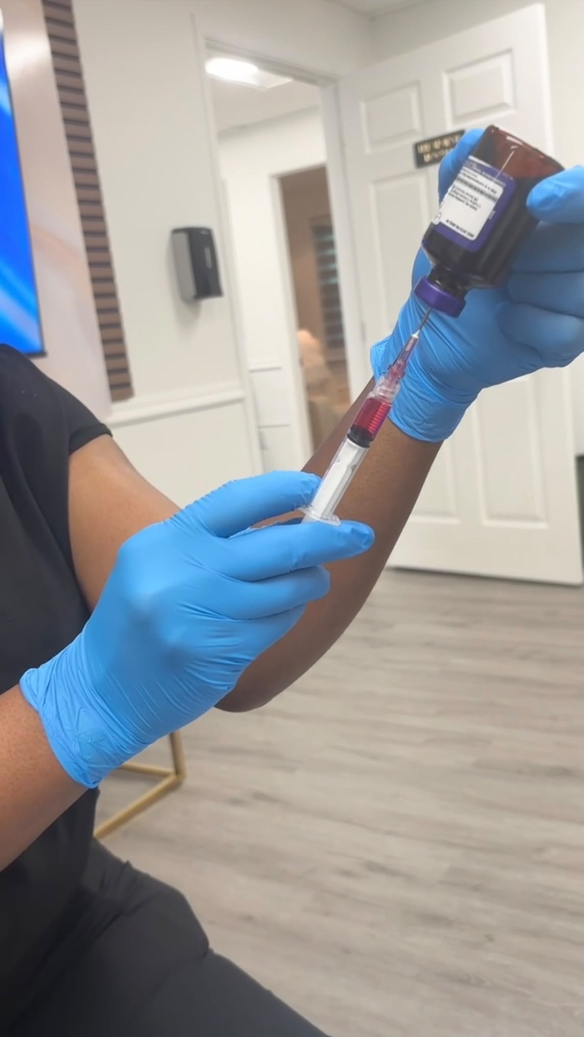 A GloVive provider in blue gloves drawing a vitamin blend from a vial into a syringe